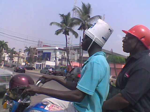An okada operator using a plastic paint container as crash helmet somewhere in Nigeria