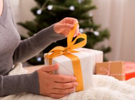 Unpacking presents. Woman opening gift box on Christmas background