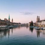 Zurich city skyline at dusk with the Limmat river reflecting lit buildings