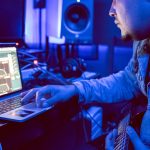 A young musician producing music on a laptop
