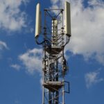 A cellular communication tower against a clear sky, the type of base station used for 5G-Advanced fixed wireless access home broadband.