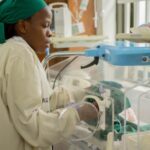 Nurse tending a newborn baby in a hospital incubator