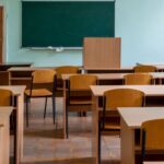 Empty classroom with wooden desks and a green chalkboard