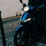 A helmeted rider on a scooter in a city street, the vehicle class Spiro and Yadea build for
