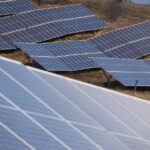 Aerial view of a large solar panel farm in an open field