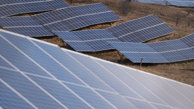 Aerial view of a large solar panel farm in an open field