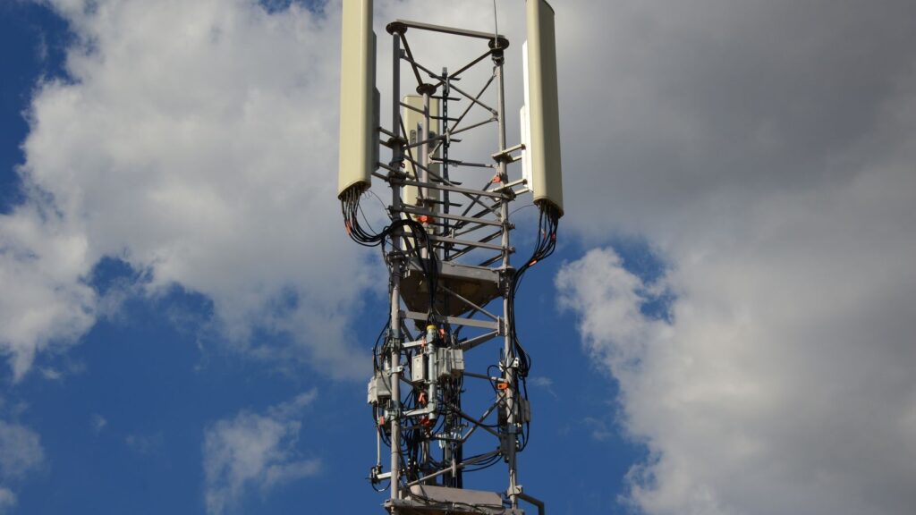 Cellular communication tower with antenna panels against a blue sky