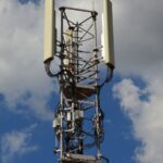 Cellular communication tower with antenna panels against a blue sky