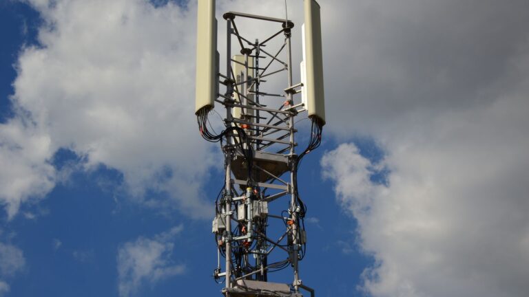 Cellular communication tower with antenna panels against a blue sky