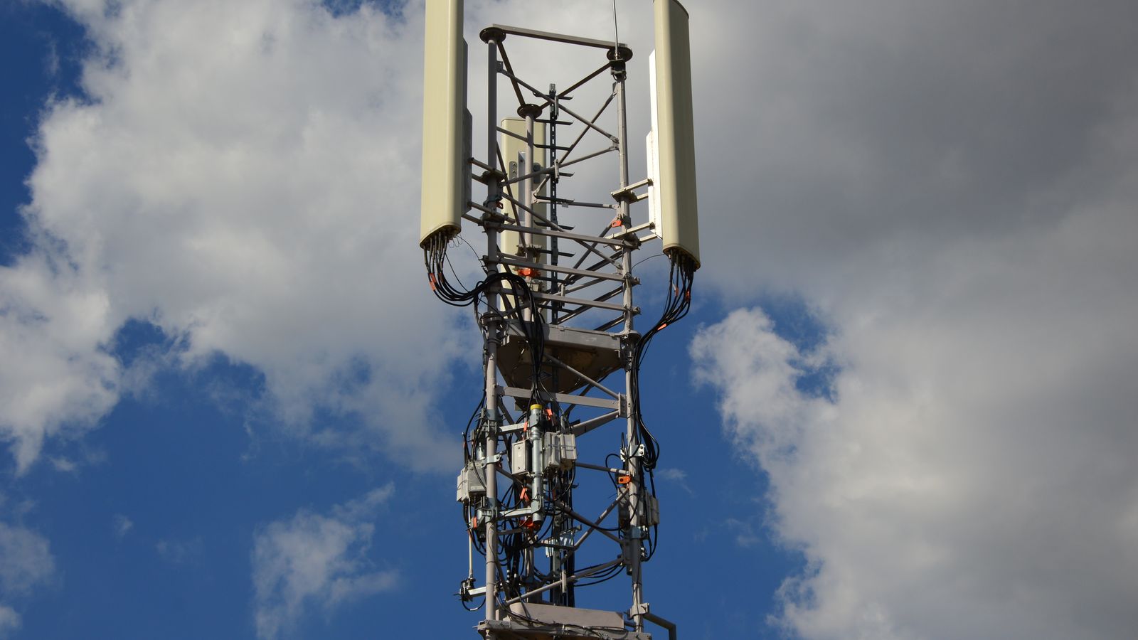 Cellular communication tower with antenna panels against a blue sky