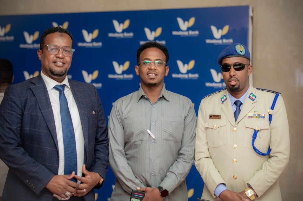 Q&A: building a digital Islamic bank in Somaliland 10 Three guests, including a uniformed Somaliland officer, in front of a Wadaag Bank branded backdrop in Hargeisa, Somaliland.