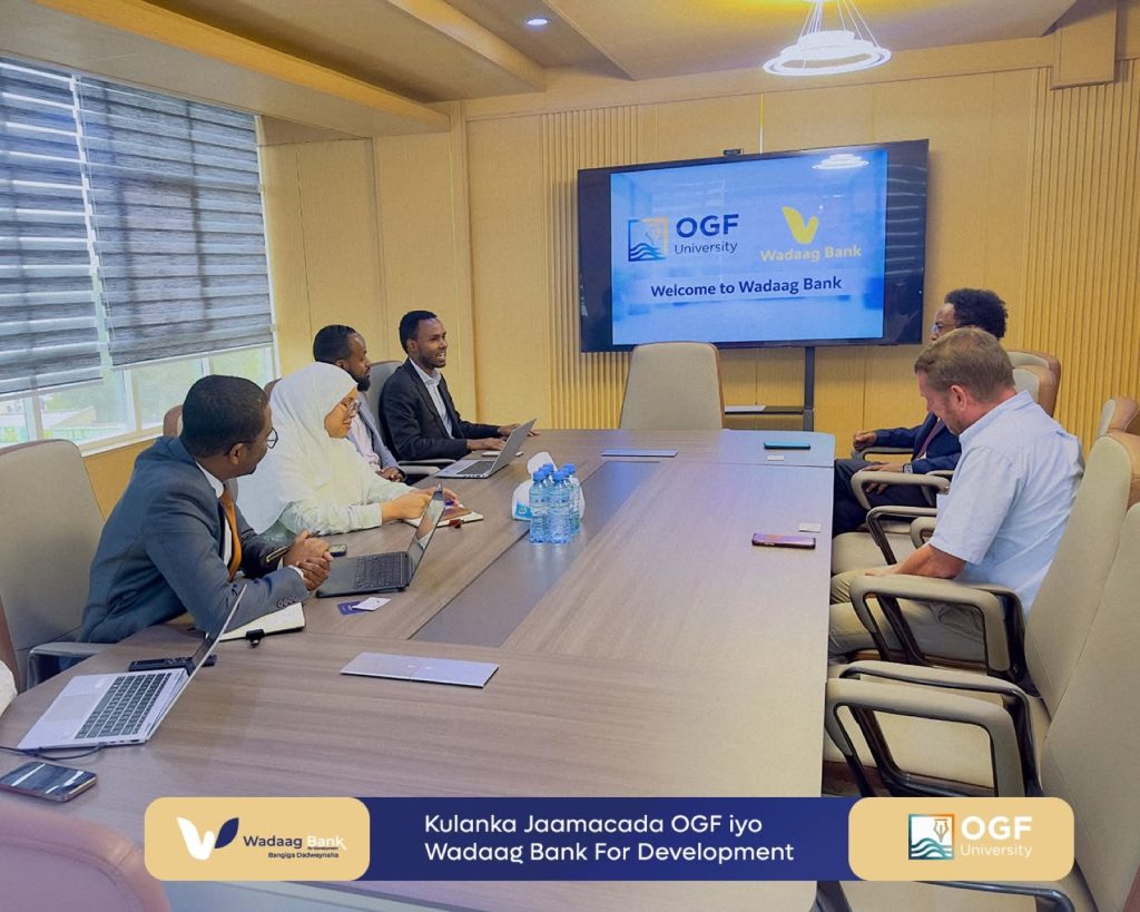 Q&A: building a digital Islamic bank in Somaliland 12 Wadaag Bank and OGF University delegates meet around a boardroom table in Hargeisa, Somaliland, beneath a joint welcome slide.